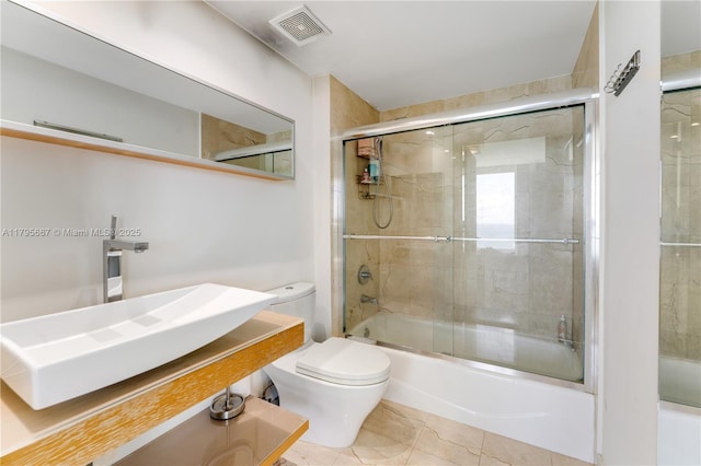 full bath featuring a sink, toilet, shower / bath combination with glass door, and visible vents