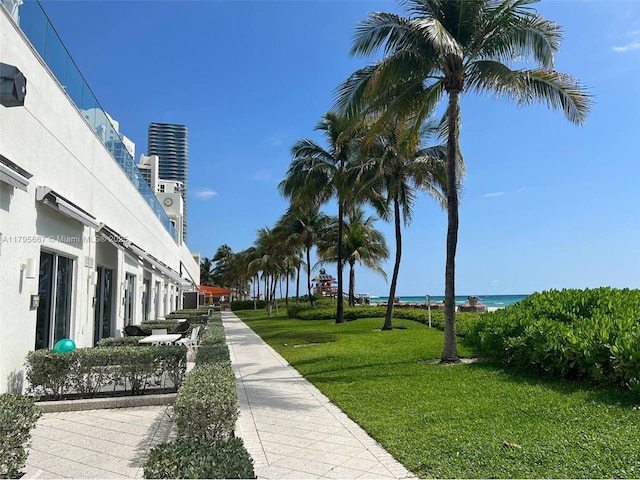 view of property's community featuring a lawn, a water view, and a beach view