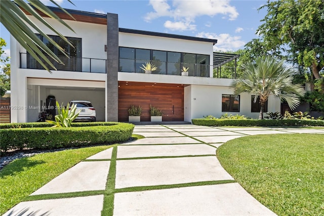 contemporary home with a front yard, driveway, a carport, and stucco siding