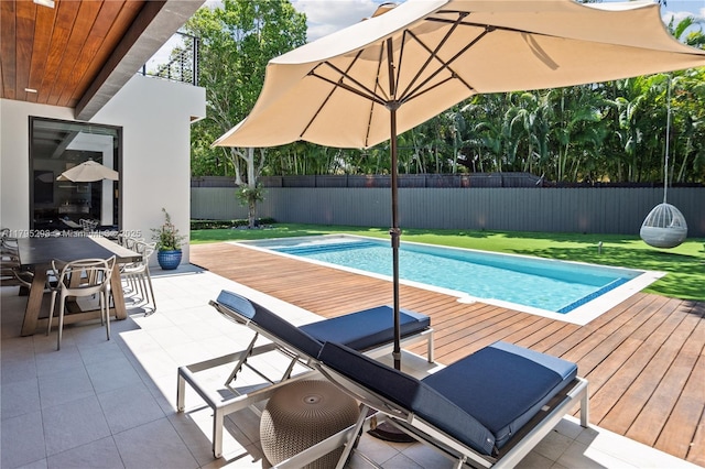 view of swimming pool featuring a wooden deck, outdoor dining area, a fenced backyard, a fenced in pool, and a yard