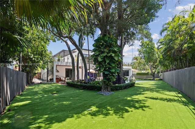view of yard with a fenced backyard and stairway