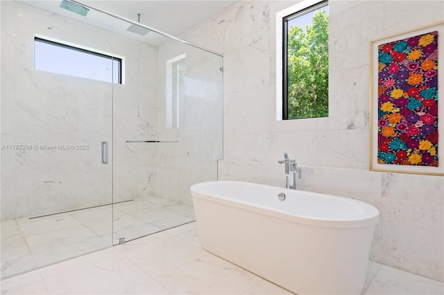 full bath with tile walls, a marble finish shower, a wealth of natural light, and marble finish floor