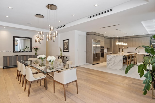 dining room with a raised ceiling, light wood-style floors, a chandelier, recessed lighting, and visible vents