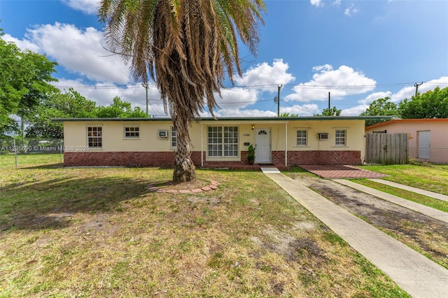 ranch-style home with brick siding, fence, and a front yard
