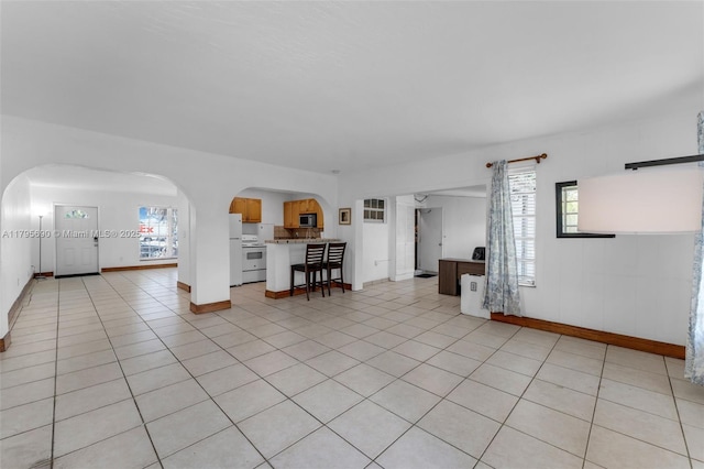 living room with arched walkways, baseboards, and a wealth of natural light