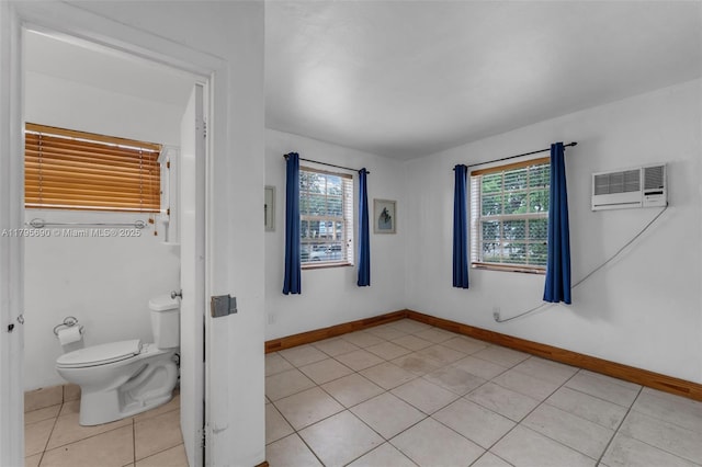 interior space featuring baseboards, tile patterned flooring, an AC wall unit, and toilet