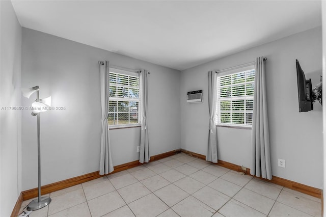 empty room featuring an AC wall unit, baseboards, and plenty of natural light