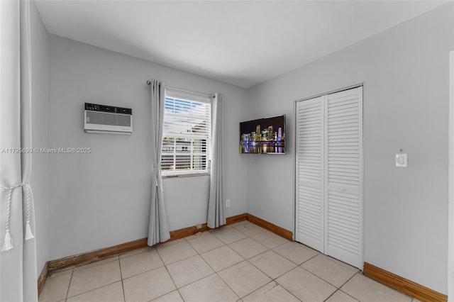 unfurnished bedroom featuring an AC wall unit, baseboards, and a closet