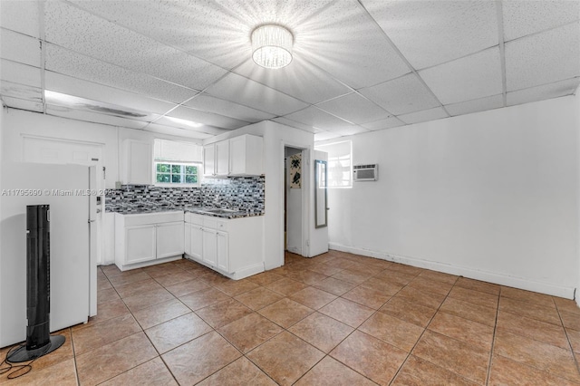 kitchen featuring a paneled ceiling, light tile patterned flooring, and white cabinets