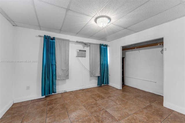 unfurnished bedroom with baseboards, a wall unit AC, tile patterned floors, and a closet