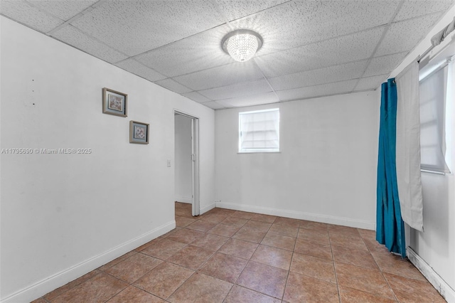 spare room with tile patterned floors, baseboards, and a paneled ceiling