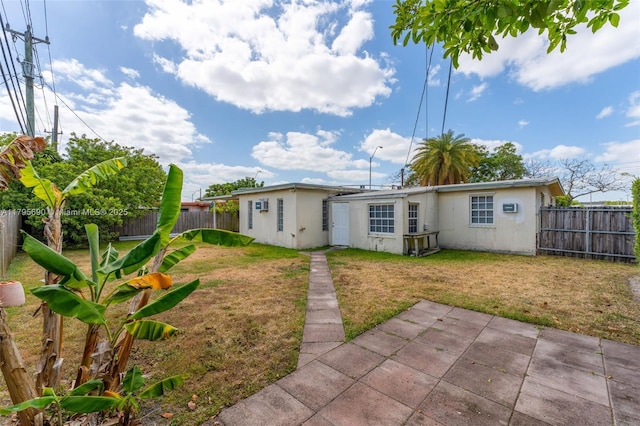 rear view of property with a yard, a patio, a fenced backyard, and stucco siding
