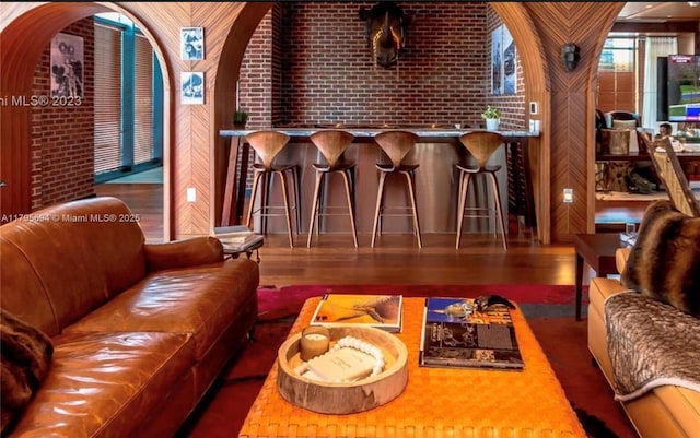 living area featuring brick wall and wood finished floors