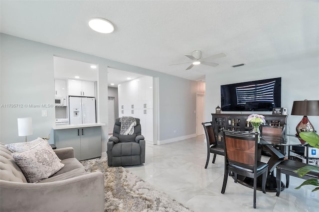 living area with a ceiling fan, baseboards, visible vents, and marble finish floor