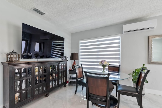 dining space featuring visible vents, a textured ceiling, and a wall unit AC