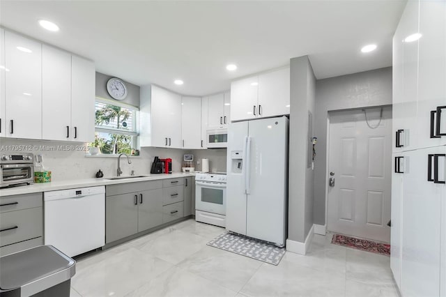 kitchen with a sink, white cabinets, white appliances, and light countertops