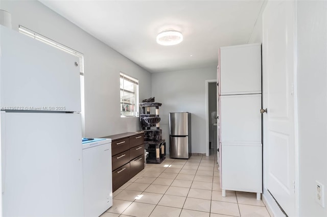 kitchen with freestanding refrigerator, light tile patterned flooring, and dark brown cabinetry