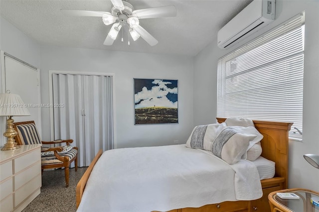 bedroom featuring a ceiling fan, a textured ceiling, a wall mounted AC, and multiple windows