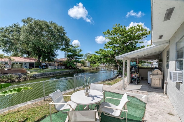 exterior space with a water view, cooling unit, a fenced backyard, and outdoor dining space