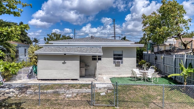 rear view of property featuring a fenced backyard, stucco siding, a gate, a shingled roof, and a lawn