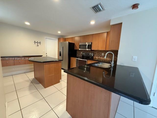 kitchen with visible vents, appliances with stainless steel finishes, dark countertops, a sink, and a peninsula