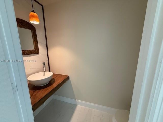 bathroom featuring a sink, baseboards, toilet, and marble finish floor