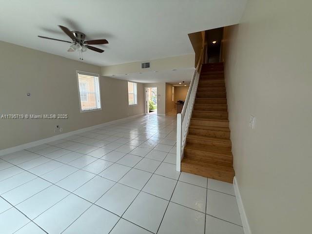 interior space with a ceiling fan, tile patterned floors, visible vents, and baseboards
