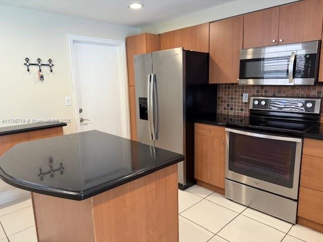 kitchen featuring light tile patterned floors, dark countertops, tasteful backsplash, and stainless steel appliances