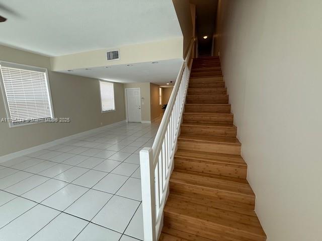 staircase featuring visible vents, baseboards, and tile patterned flooring