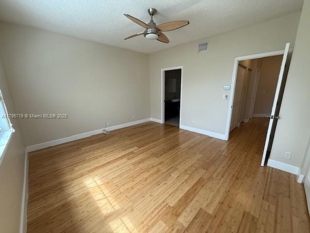 spare room with ceiling fan, light wood finished floors, a textured ceiling, baseboards, and visible vents