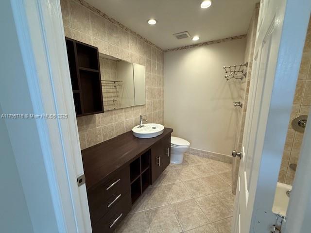full bathroom with tile patterned flooring, vanity, toilet, tile walls, and visible vents