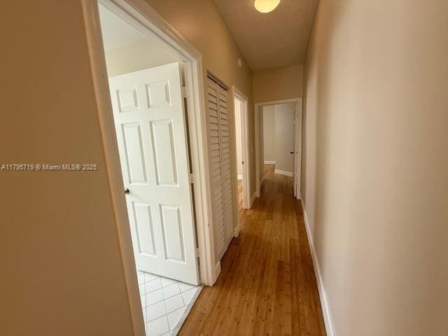 corridor featuring baseboards and light wood-type flooring