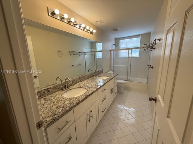 bathroom with tile patterned flooring, a sink, double vanity, and toilet