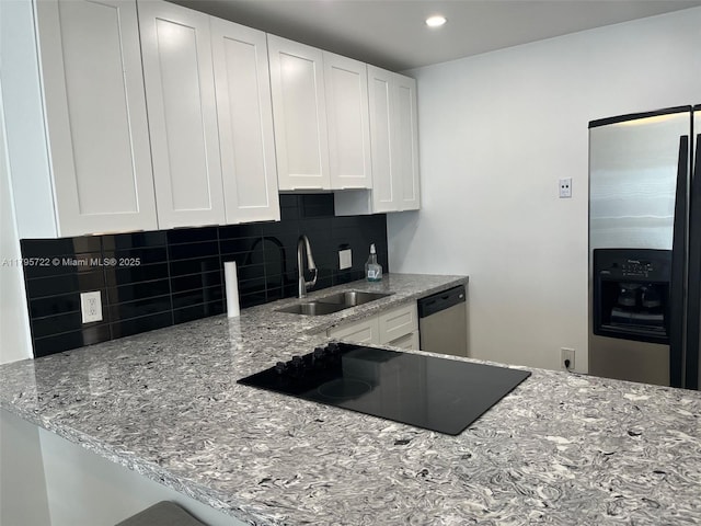 kitchen with decorative backsplash, white cabinetry, light stone counters, a sink, and appliances with stainless steel finishes