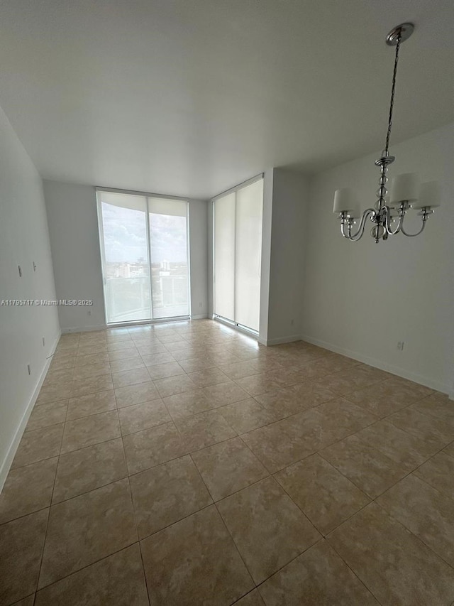 tiled spare room featuring baseboards, floor to ceiling windows, and a chandelier