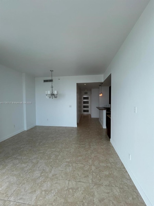 unfurnished living room featuring an inviting chandelier, baseboards, and visible vents