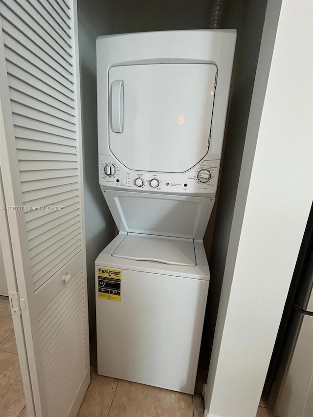 laundry room featuring laundry area, light tile patterned floors, and stacked washer and clothes dryer