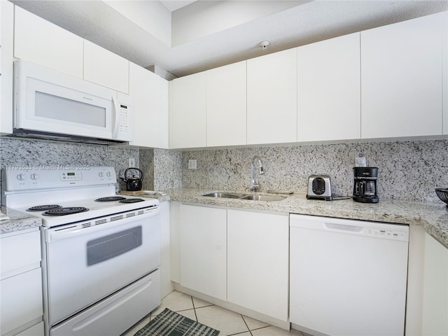 kitchen with light tile patterned flooring, white appliances, white cabinetry, a sink, and backsplash