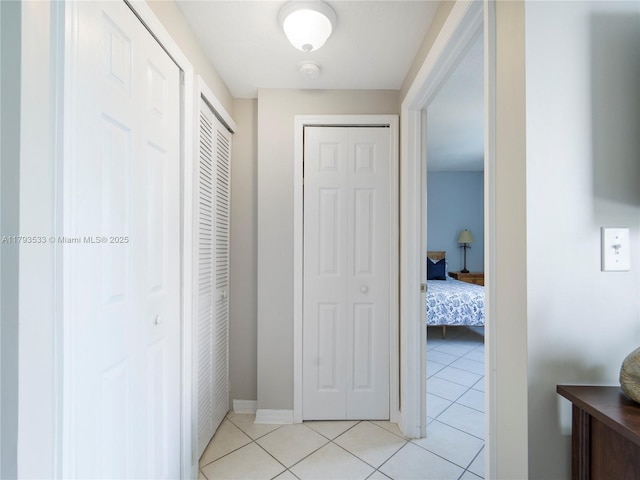corridor featuring baseboards and light tile patterned floors