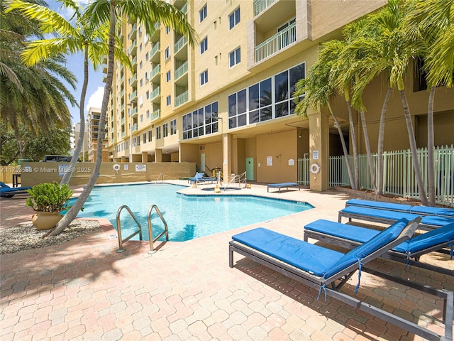 community pool with fence and a patio