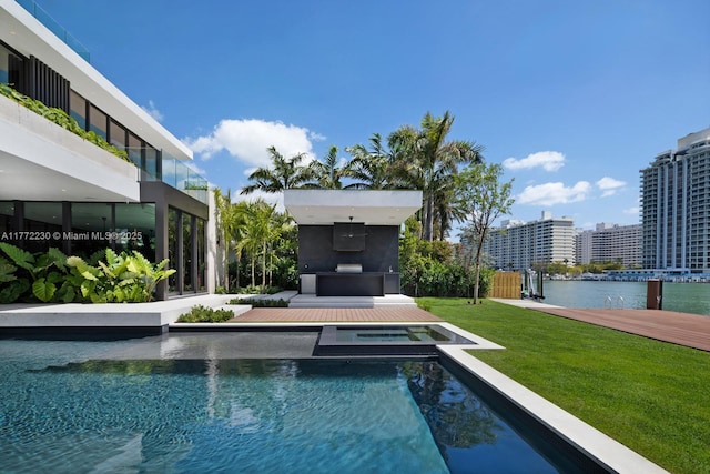 5515 Pine Tree Dr, Miami Beach, FL 33140 - view of swimming pool with a yard, a water view, and a pool with connected hot tub