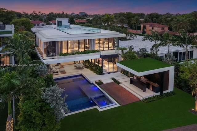 5515 Pine Tree Dr, Miami Beach, FL 33140 - back of house at dusk featuring a patio area, a balcony, a lawn, and a pool with connected hot tub