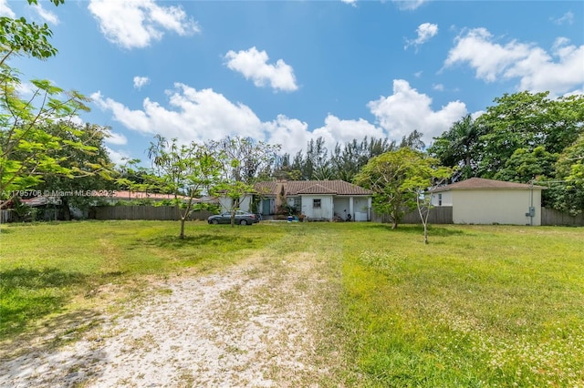 exterior space featuring fence, driveway, and a front lawn