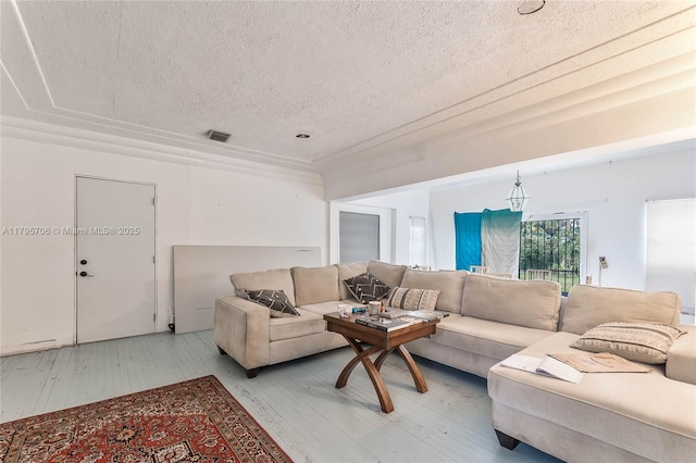 living room featuring light wood-type flooring, a textured ceiling, and visible vents