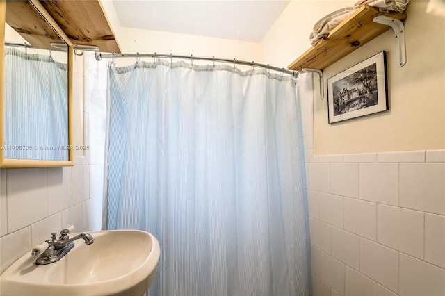 full bath featuring tile walls, curtained shower, and a sink