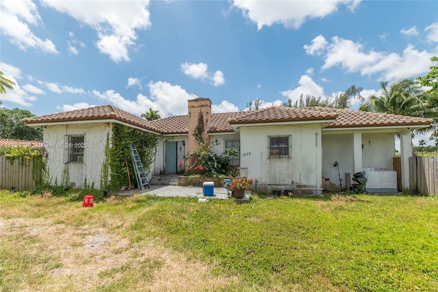 back of property featuring a chimney, a tile roof, fence, a yard, and stucco siding