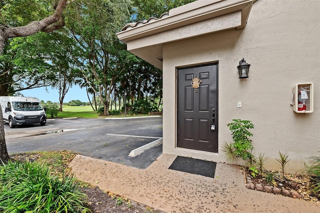 view of exterior entry featuring stucco siding and uncovered parking