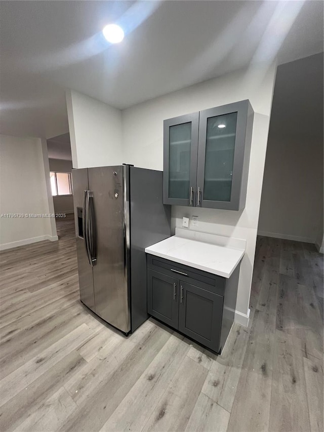 kitchen with gray cabinets, baseboards, light wood finished floors, and stainless steel fridge with ice dispenser