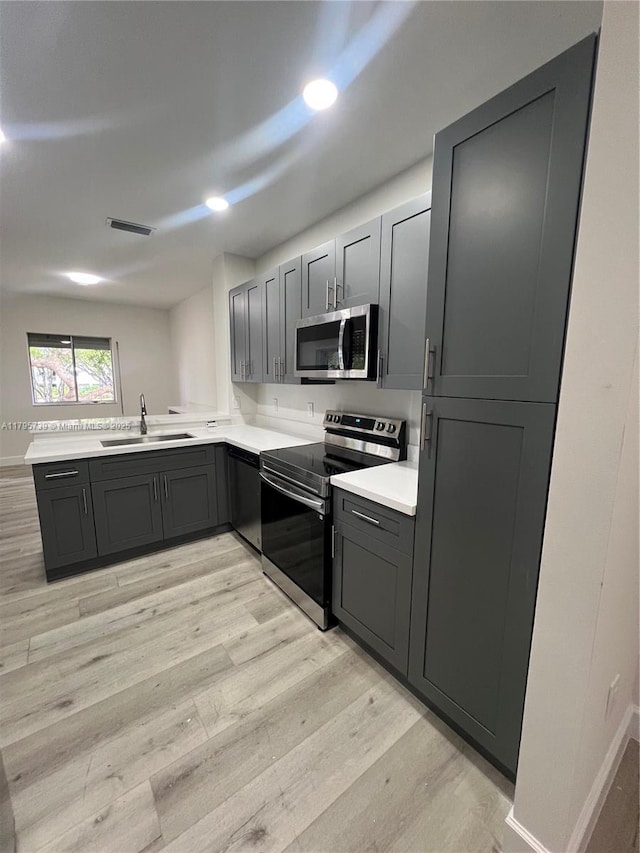 kitchen featuring a sink, gray cabinets, stainless steel appliances, light wood-type flooring, and visible vents