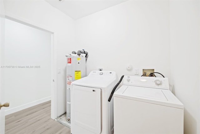 clothes washing area featuring light wood-style floors, laundry area, baseboards, water heater, and separate washer and dryer